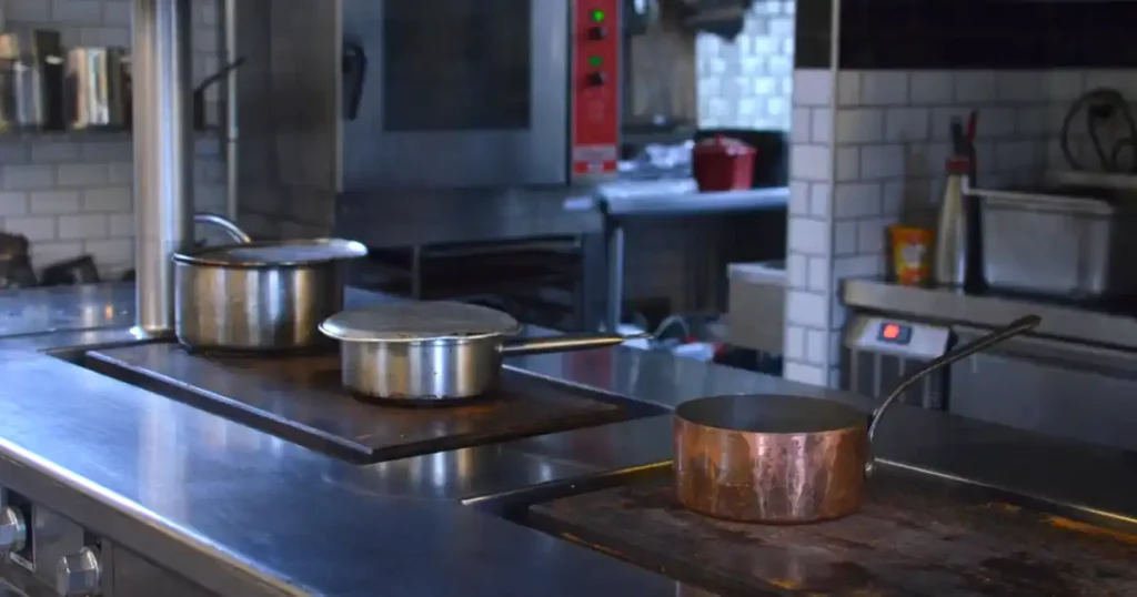 Cocina profesional de restaurante limpia, con cazos sobre la encimera de acero inoxidable